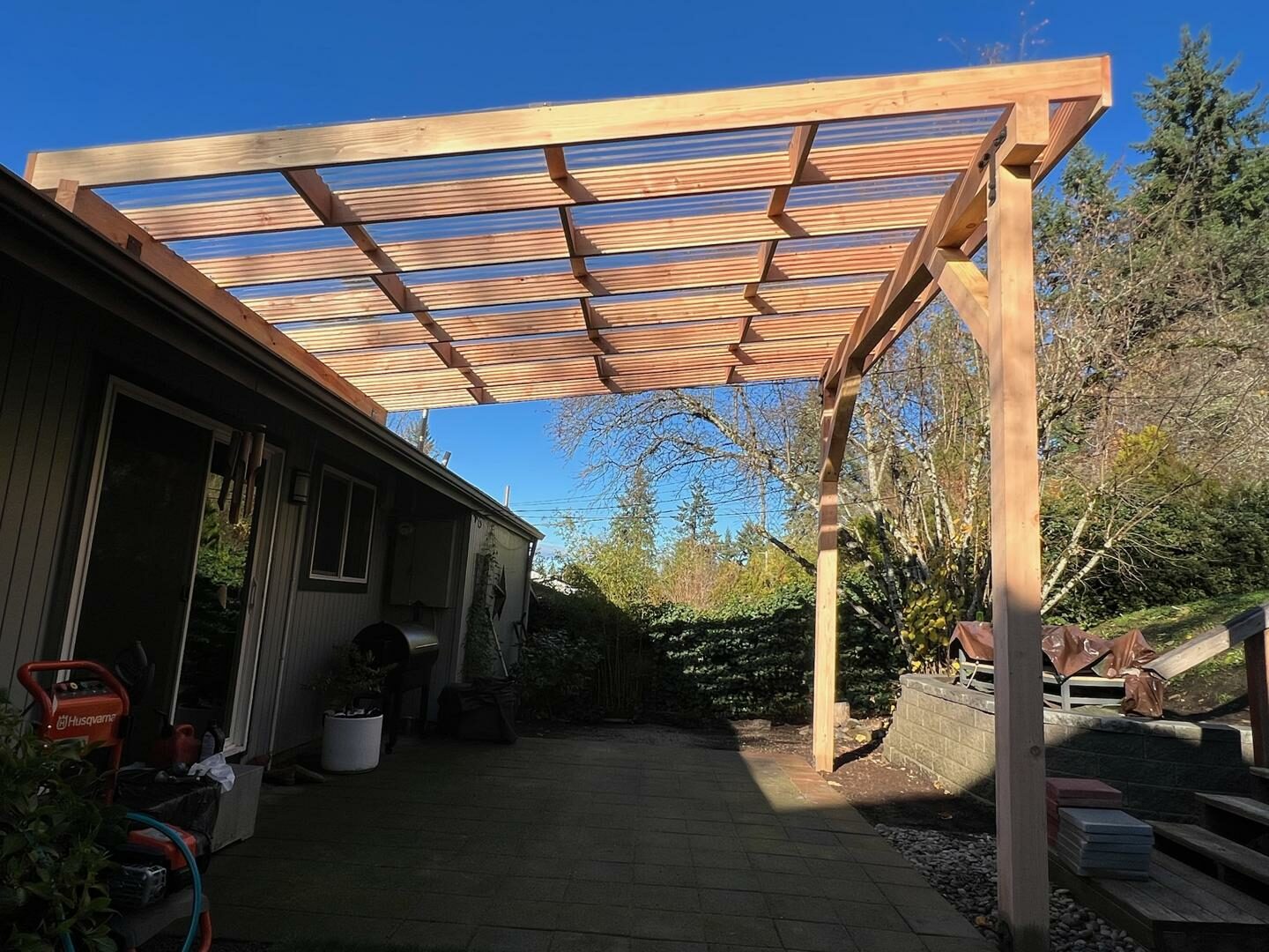 Wooden pergola installed over a backyard patio, designed for shade and outdoor gatherings.