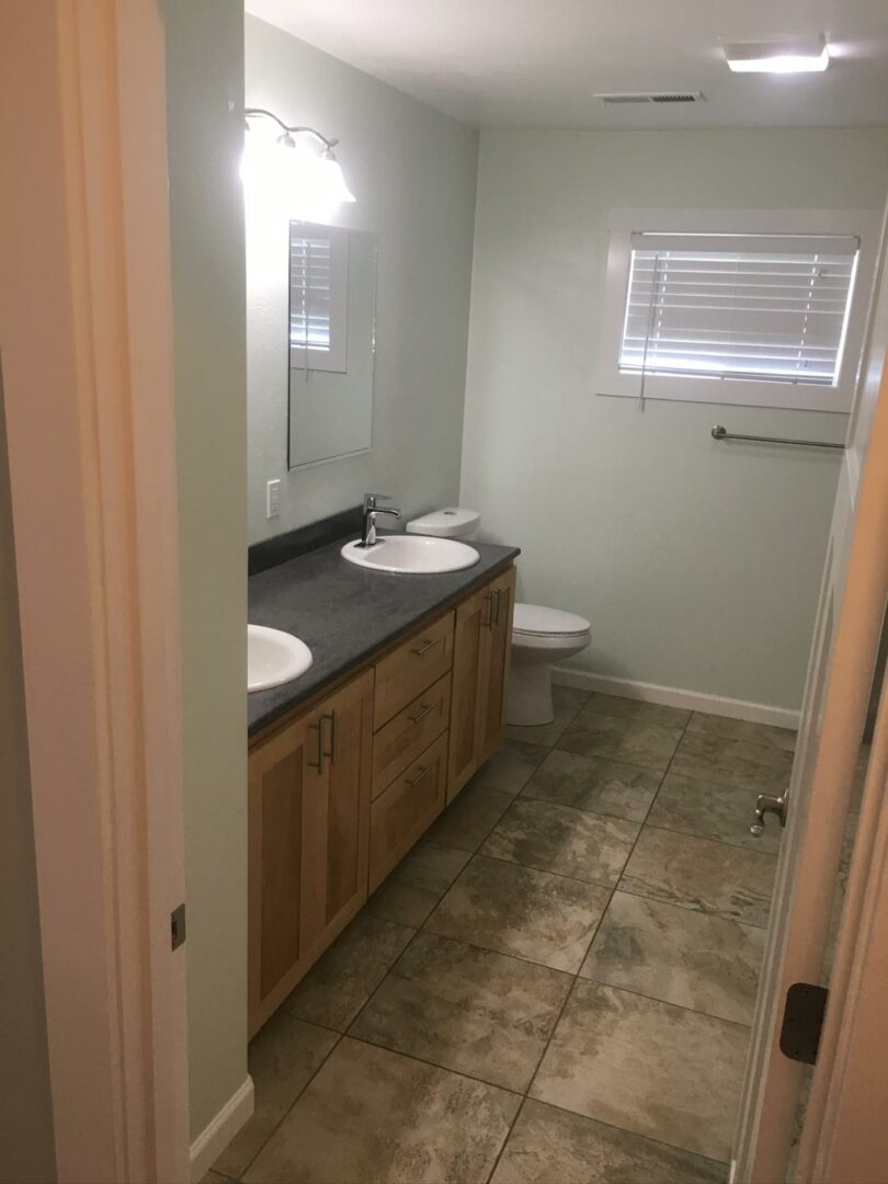 Bathroom remodel with updated double-sink vanity, tile flooring, and fresh wall finishes.