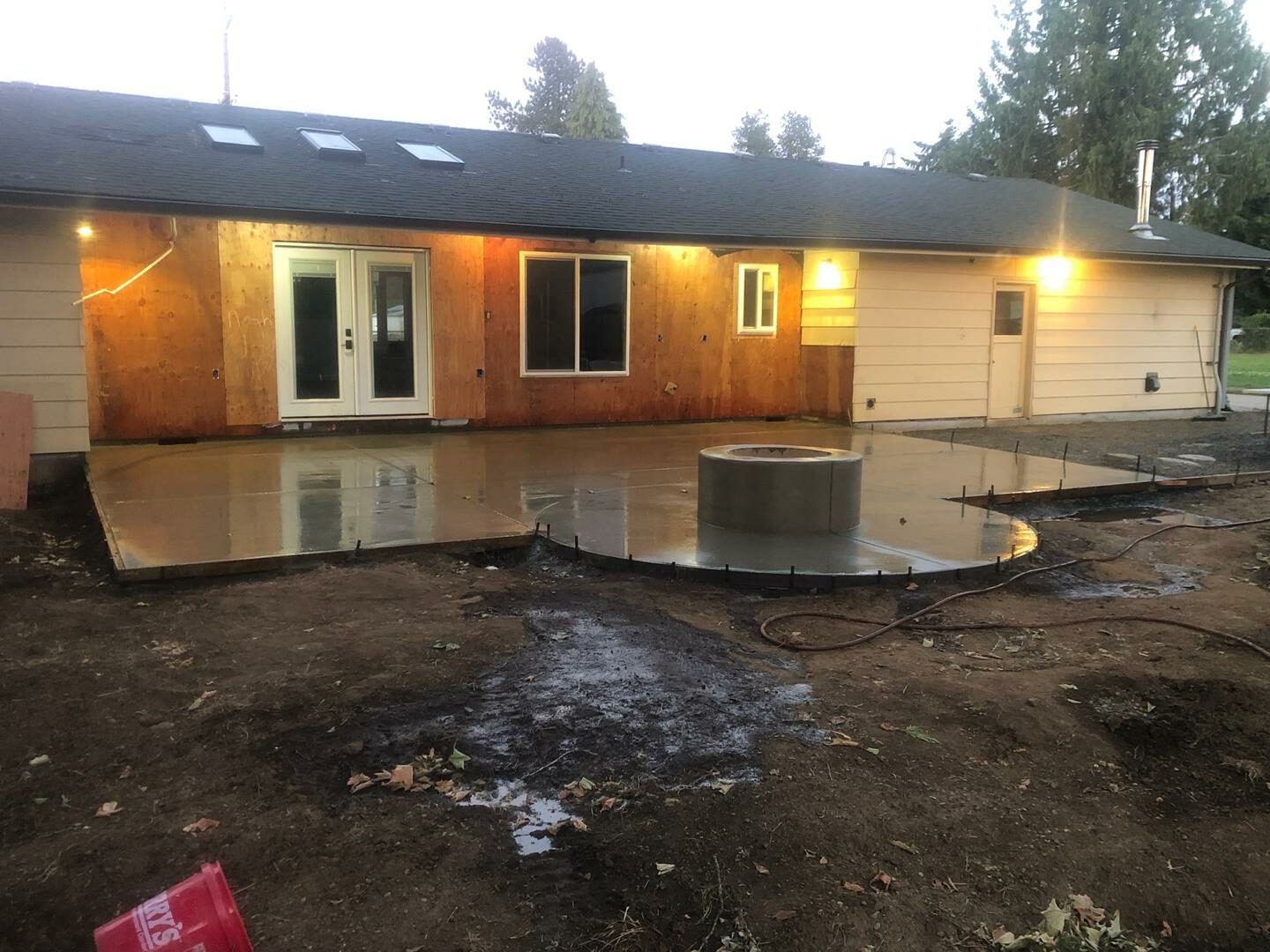 Modern home exterior renovation featuring a new concrete patio and custom fire feature in Eugene, Oregon.
